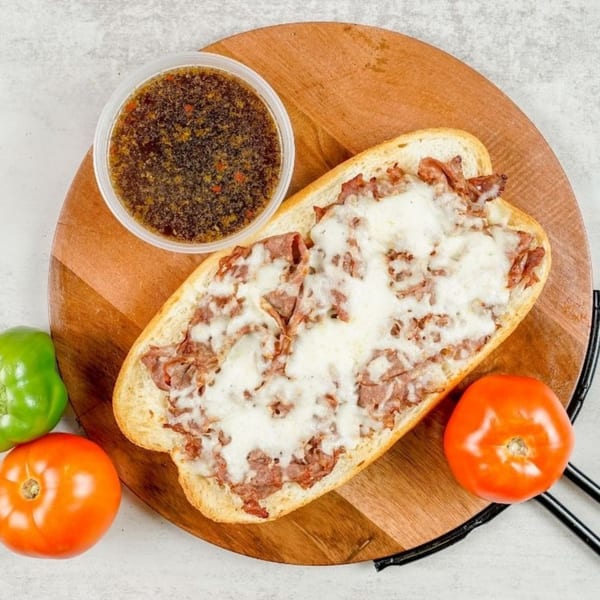 South Lake Pizza's cheesy steak sandwich with a side of au jus, tomato, and green pepper.