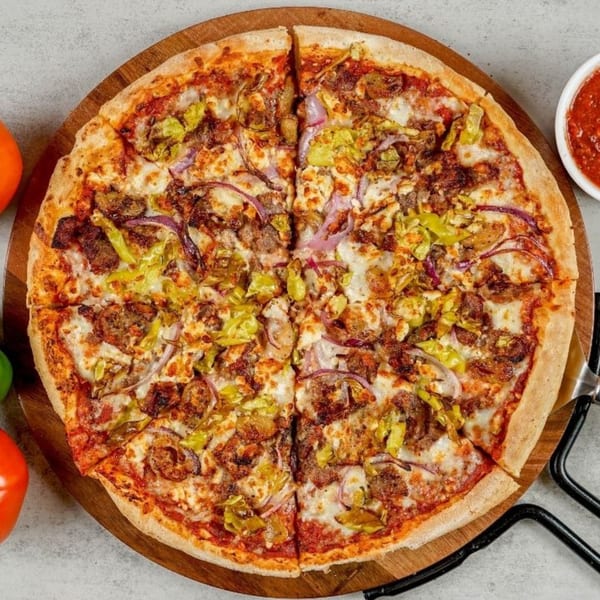 South Lake Pizza's whole pizza with sausage, green peppers, and red onions on a wooden board.