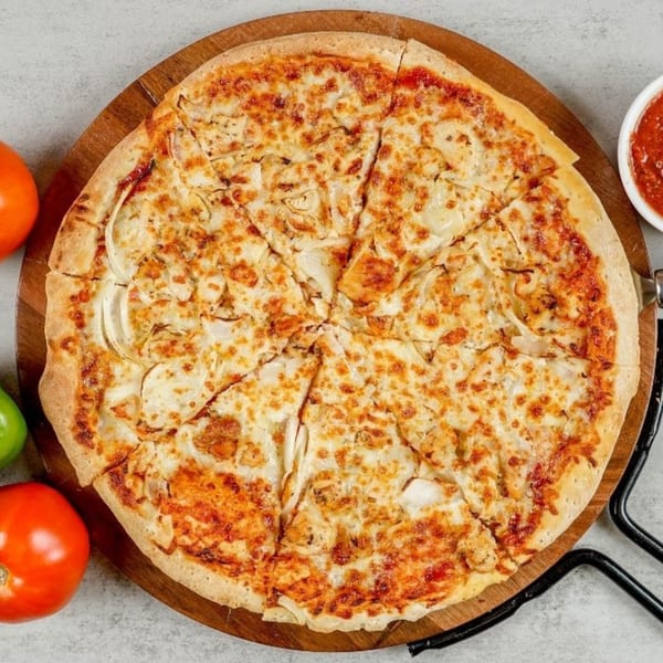 A South Lake Pizza chicken and onion pizza, sliced on a wooden board with tomatoes and sauce.