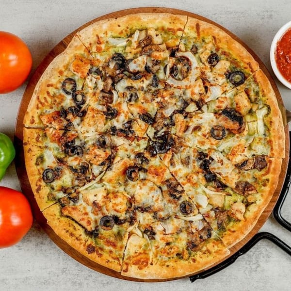 A South Lake Pizza with chicken, olives, mushrooms, and onions on a wooden board.