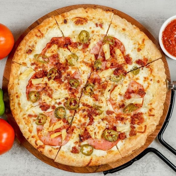 South Lake Pizza's sliced pizza with ham, pineapple, jalapeños, and bacon on a wooden board.